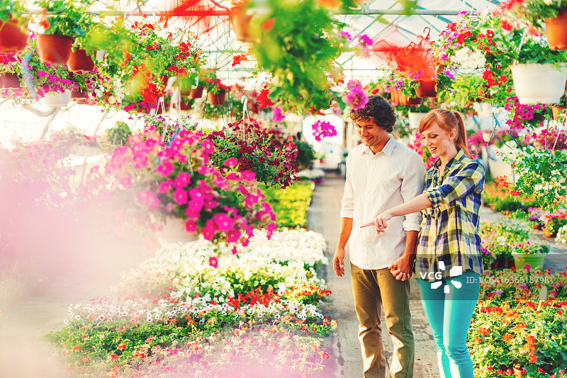 在花卉苗圃购买室内盆栽植物的年轻人图片素材