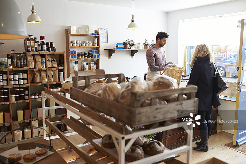 在熟食店为女性顾客服务的男销售助理图片素材