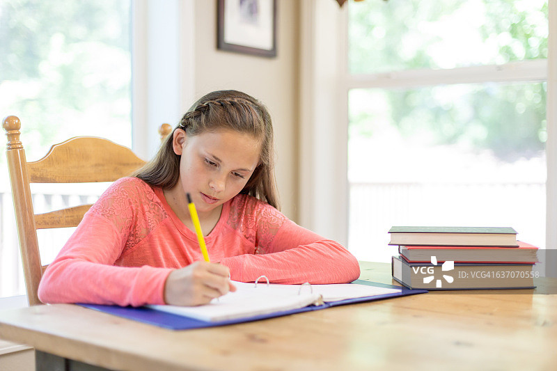 小学生在厨房的餐桌上做作业图片素材