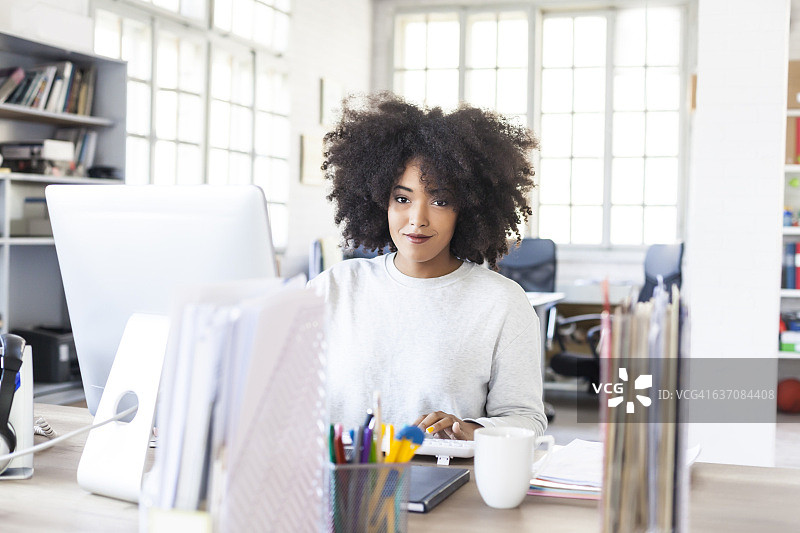 在现代工作场所使用电脑的微笑女人图片素材
