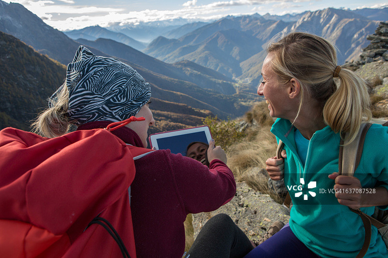 两位在山顶上使用平板电脑的年轻女人图片素材