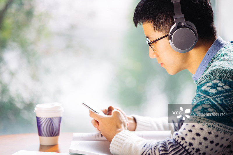手持手机的亚洲男学生图片素材