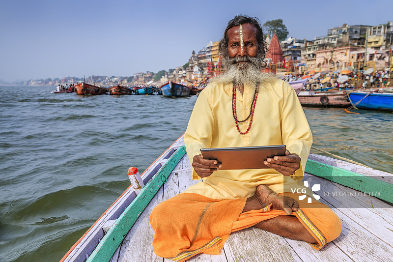 苦行僧在瓦拉纳西恒河的船上使用平板电脑图片素材