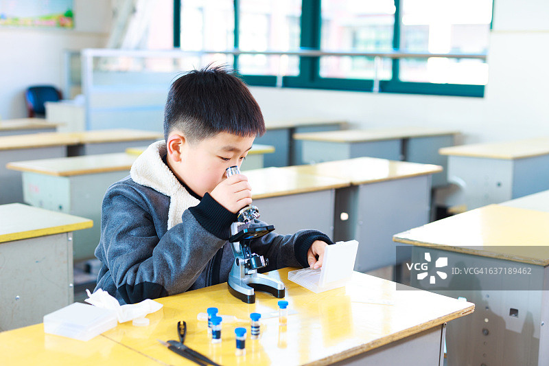 亚洲小学生在教室里用显微镜做实验图片素材