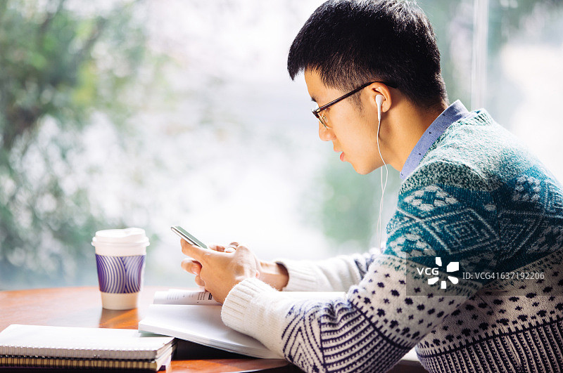 手持手机的亚洲男学生图片素材