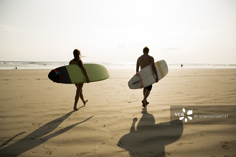 携带冲浪板行走的两人图片素材