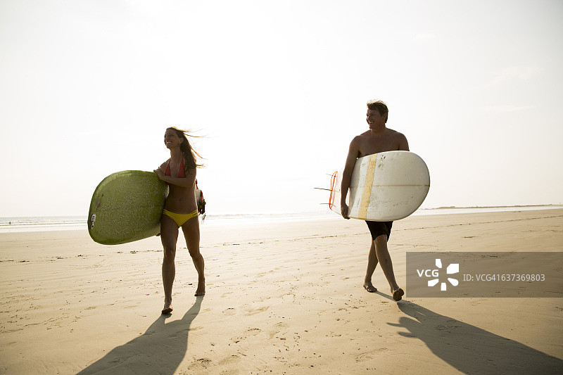 携带冲浪板行走的两人图片素材