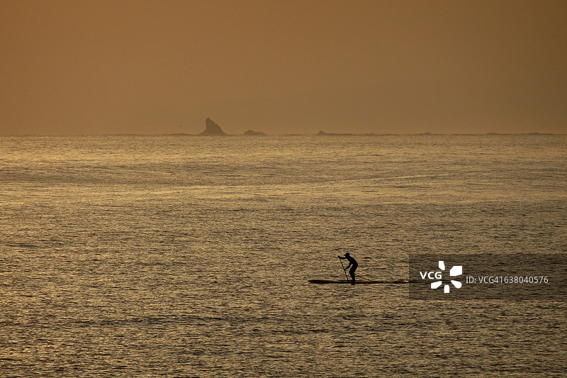 在日落海滩上玩桨板图片素材