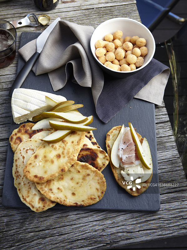 扁平面包、塔雷吉欧干酪、梨片、意式熏火腿和澳洲坚果的俯视图图片素材