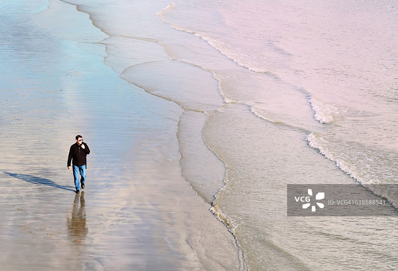 中年男人在海滩海岸线上行走图片素材