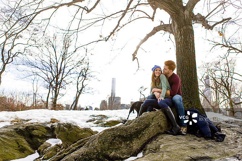 在纽约中央公园雪地里和狗一起的浪漫情侣图片素材