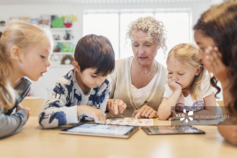 老年教师和使用图表及平板电脑的孩子们图片素材