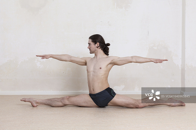 自信的男人伸展双臂做瑜伽劈叉图片素材