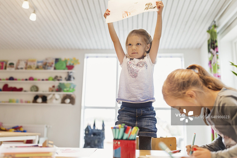 小女孩在教室里展示画作图片素材