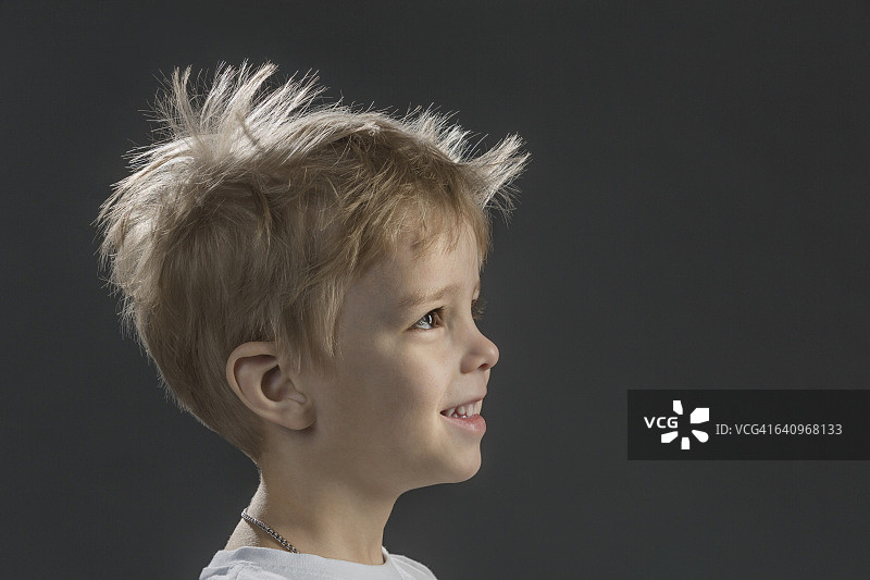 快乐男孩在灰色背景下的侧面特写图片素材