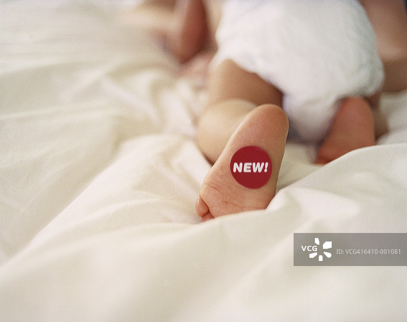 脚上贴着“New”标签的婴儿图片素材
