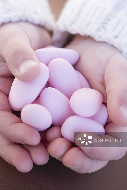 儿童的手拿着粉红色的糖渍杏仁图片素材