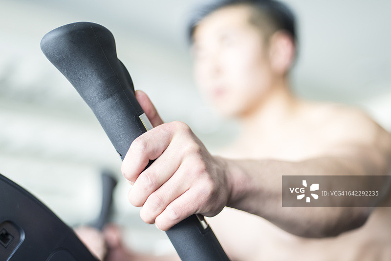 男人在健身房的椭圆机上图片素材