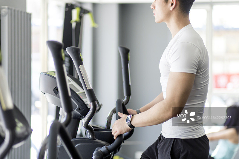 男人在健身房的椭圆机上图片素材