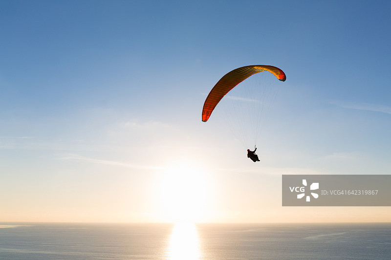 日落时分在海洋上航行的滑翔伞图片素材