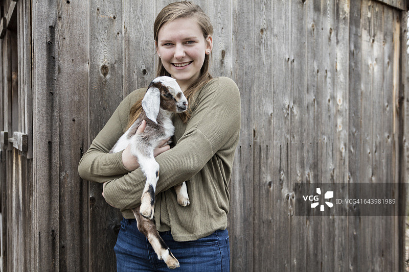 抱着小山羊的年轻女子肖像图片素材