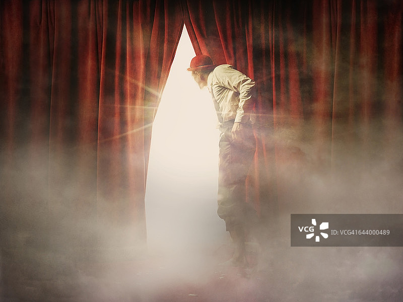 透过红色窗帘窥视的白人男子图片素材