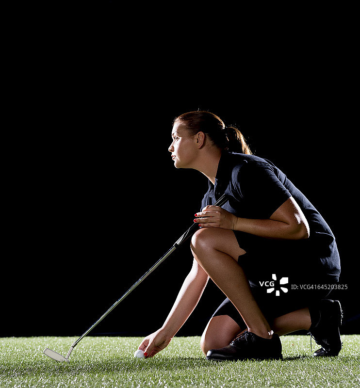 黑色背景下的女高尔夫球手图片素材