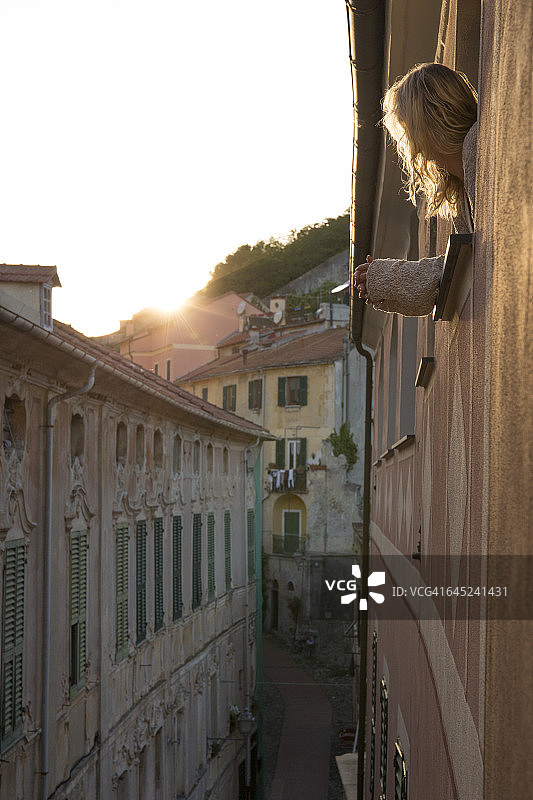 探出窗外观看日出的女人图片素材