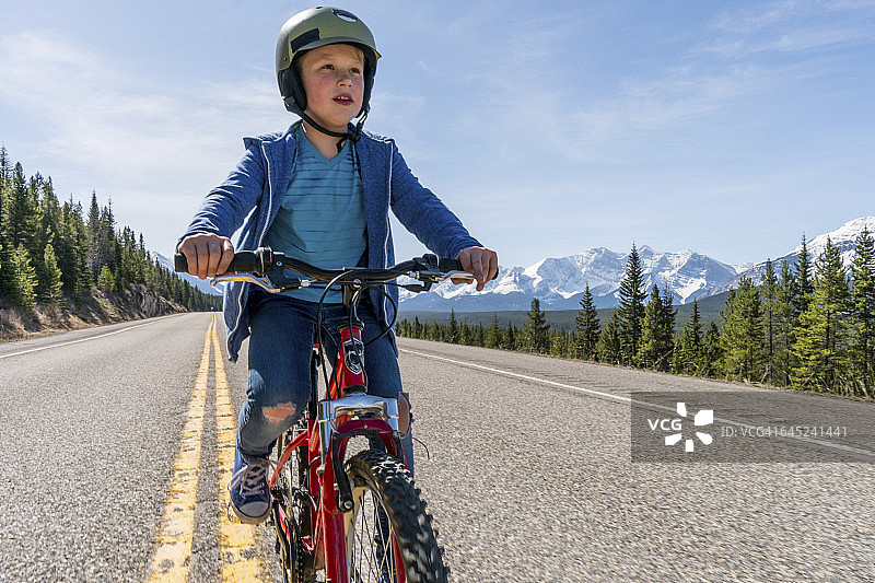 在铺好的山路上骑自行车的男孩图片素材