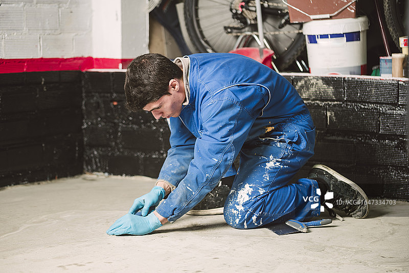 砌砖工人用刮刀去除地面找平层的不规则之处图片素材