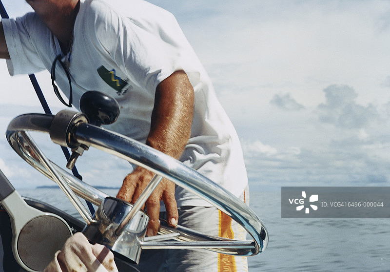 男人在船舵旁。图片素材