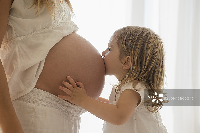 白人女孩亲吻怀孕母亲的肚子图片素材
