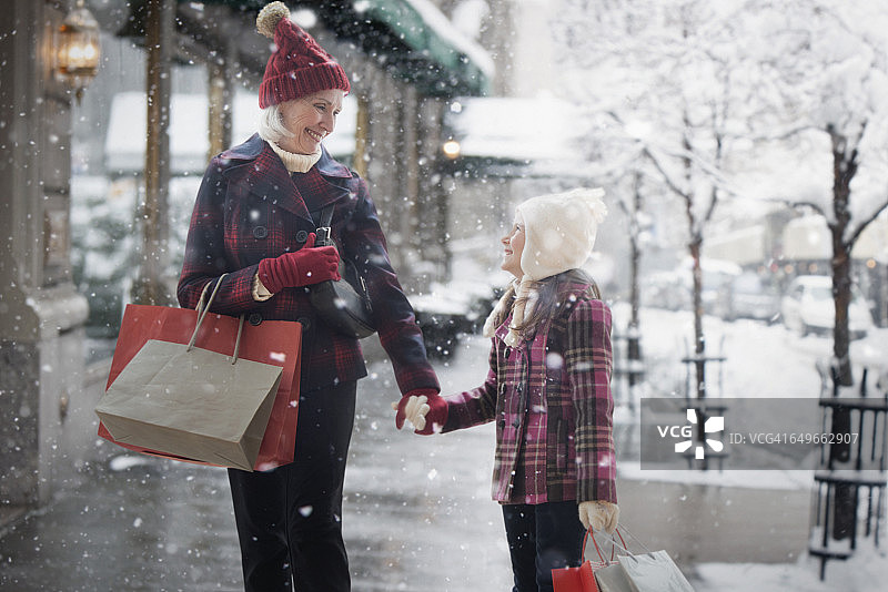 在雪地里购物的白人祖母和孙女图片素材