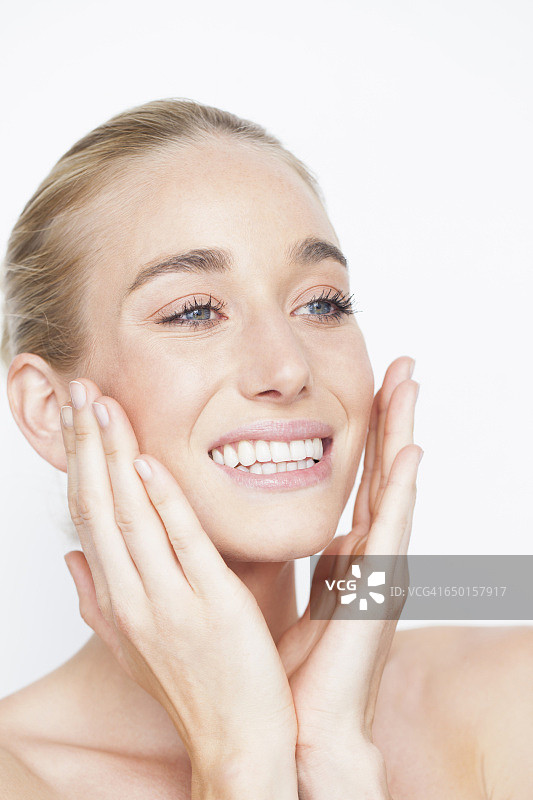 露出肩膀的女人双手抚面，面带微笑向远处望去图片素材