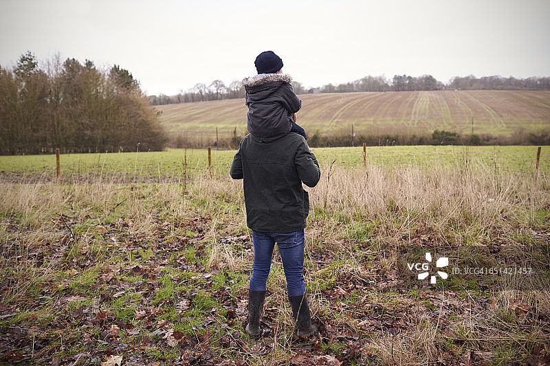 父亲在乡村散步时让儿子骑在肩上图片素材