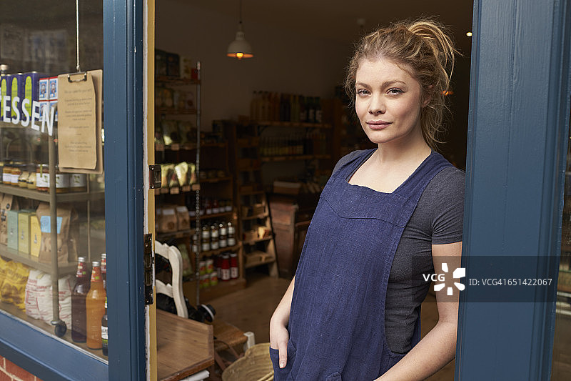 站在商店门口的女熟食店店主肖像图片素材