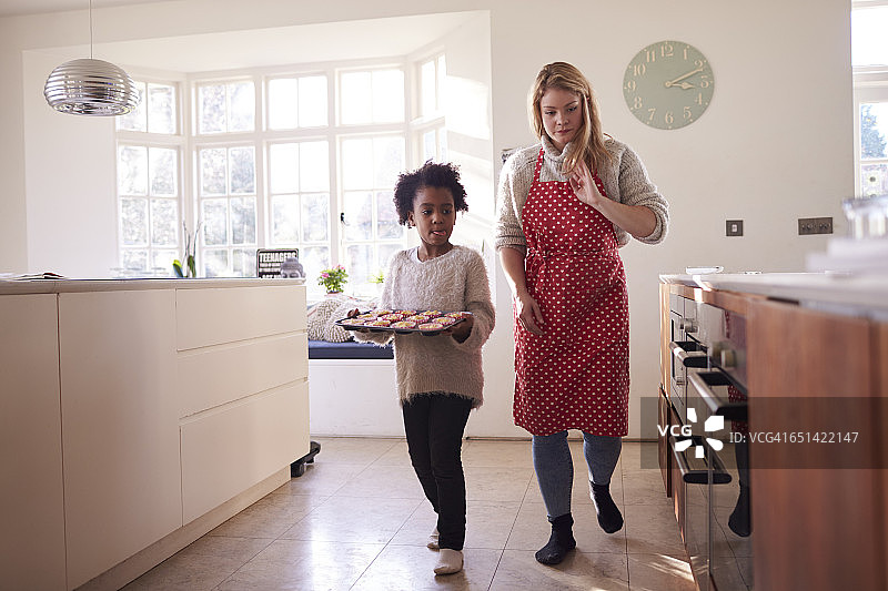 母女拿着准备放入烤箱的纸杯蛋糕图片素材