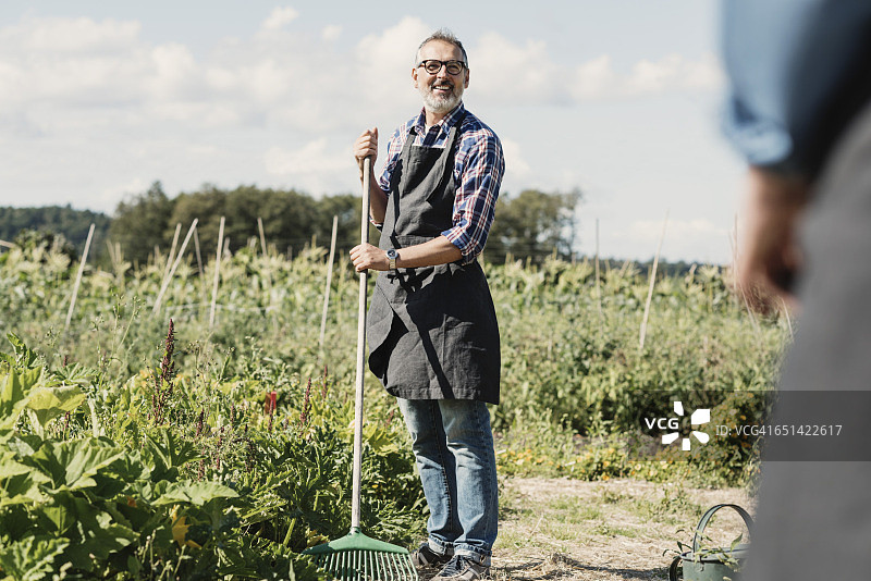 中年农场主拿着园艺叉和同事一起站在农场图片素材