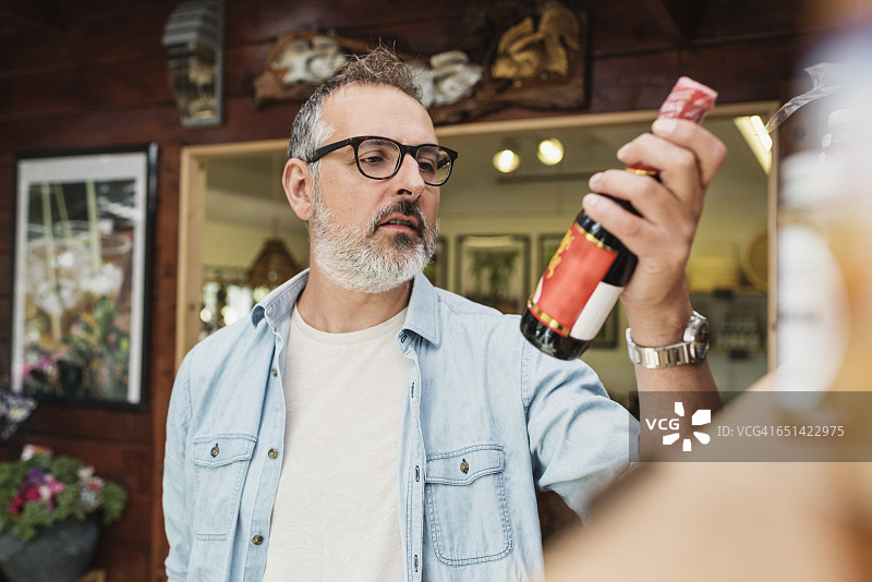 中年男人在商店查看瓶子上的信息图片素材