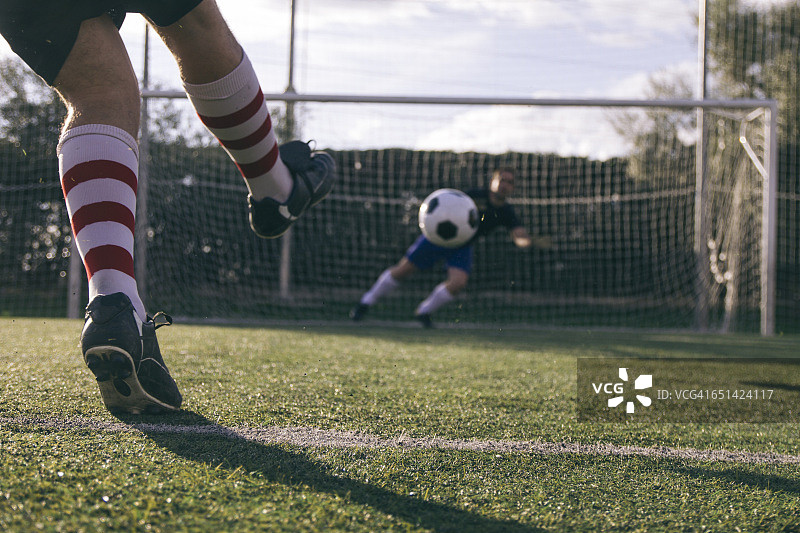 足球运动员在守门员面前踢球的腿图片素材