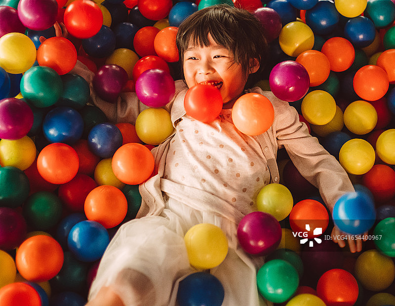 小女孩在球池中快乐玩耍图片素材