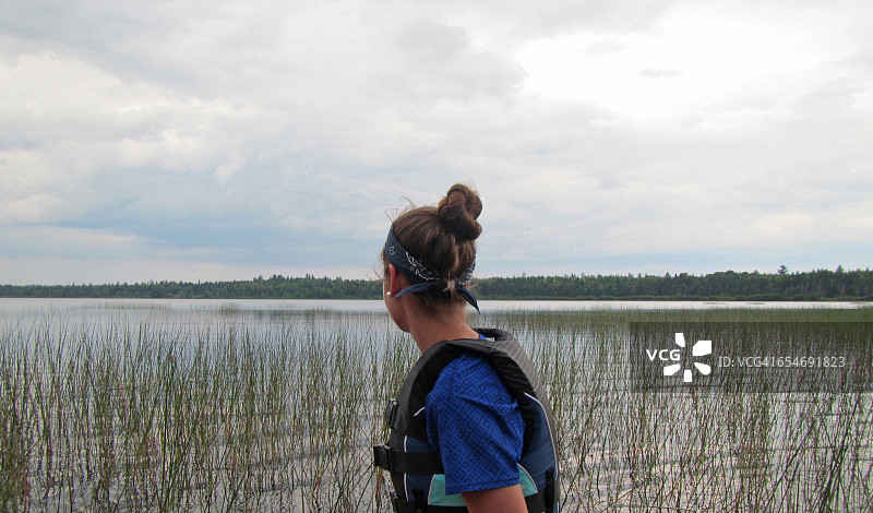 年轻女孩眺望长满青草的湖面图片素材