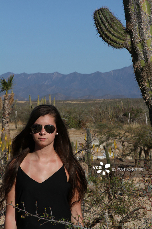 在沙漠中戴飞行员太阳镜的年轻女孩图片素材