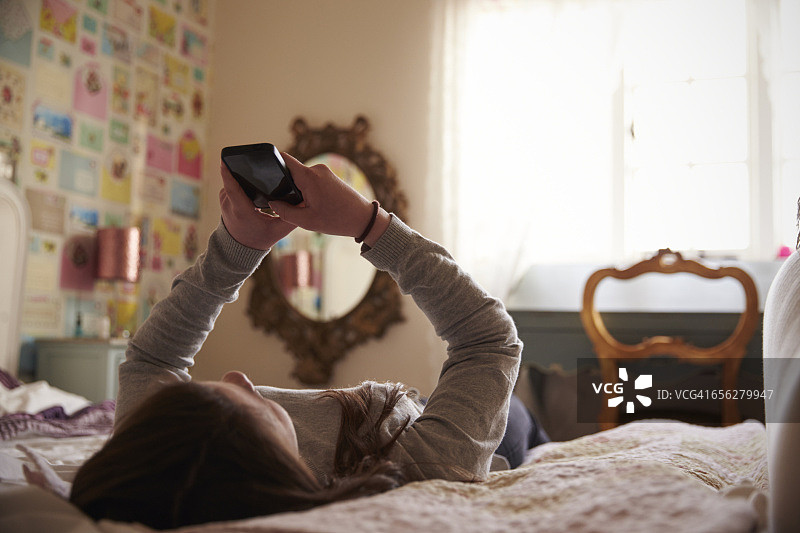 在家中卧室使用手机的少女图片素材