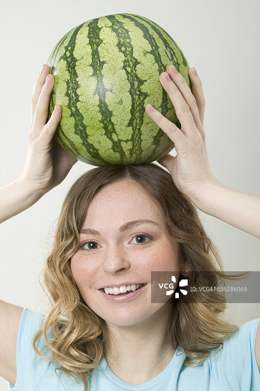 女人头顶西瓜保持平衡图片素材
