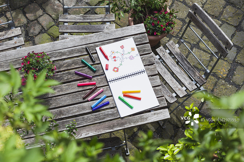 绘画，速写本，木制花园桌上的绘画和彩色铅笔图片素材