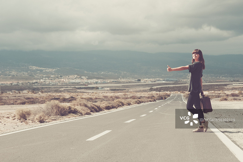 在路上搭便车的年轻女人和行李箱图片素材