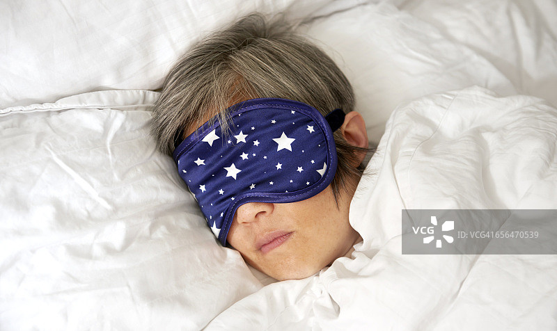 戴着眼罩在床上睡觉的中年妇女特写图片素材