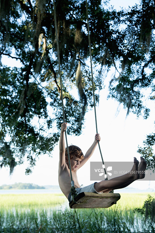 在花园木制秋千上的小男孩图片素材