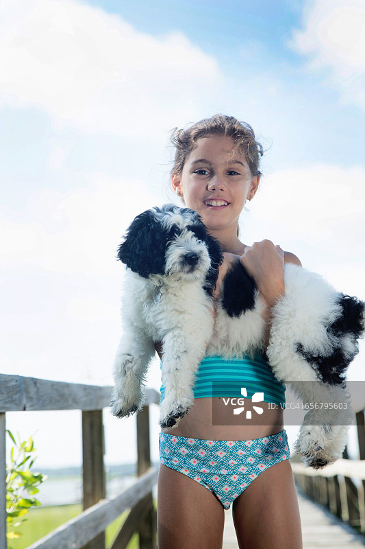 快乐的年轻女孩在户外抱着她的幼犬图片素材